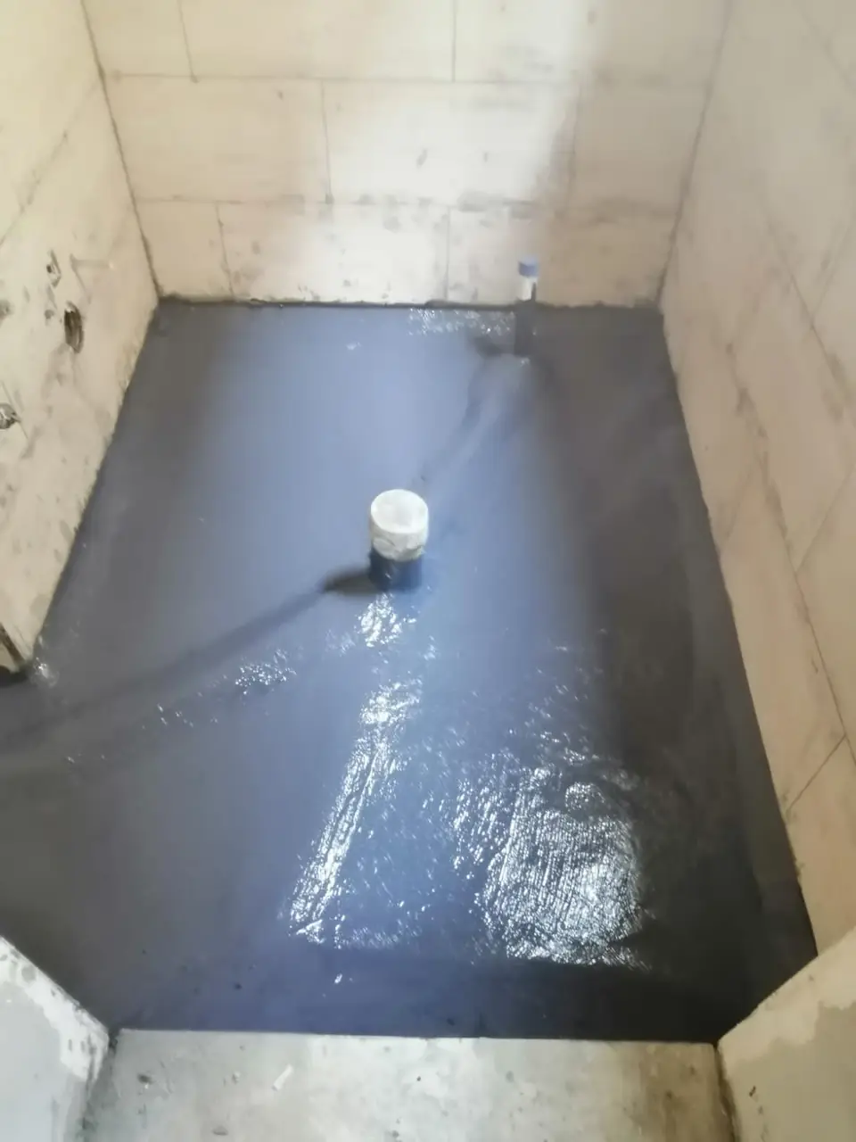 Continuous bitumen waterproofing in a bathroom before tiling
