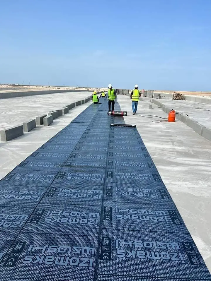 فريق العمل أثناء فرد رولات البيتومين على السطح